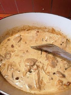 a pan filled with meat and mushrooms in gravy next to a spatula