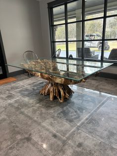 a table made out of driftwood and glass top with chairs in front of it