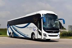 a white and blue bus parked in a parking lot next to some grass on a cloudy day