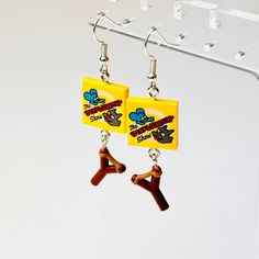 the earrings are made out of plastic and have cartoon characters on them, as if they were dangling from earwires