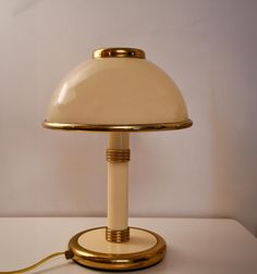 a lamp that is sitting on top of a white tablecloth with a gold base