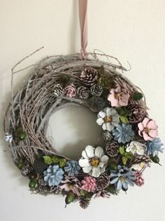 a wreath is hanging on the wall with pine cones and flowers