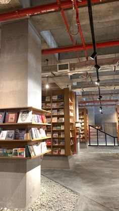 the inside of a book store with many books on shelves and lights hanging from the ceiling