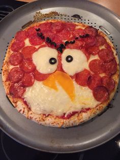 a pizza with pepperoni and an angry bird on it's face is sitting in a frying pan