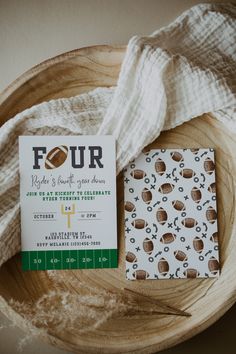 a football themed baby shower is displayed on a wooden bowl next to a white and green ticket