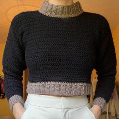 a close up of a person wearing white pants and a black knitted sweater with an open collar