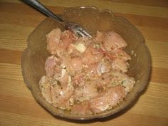 a bowl filled with meat and vegetables on top of a wooden table next to a fork