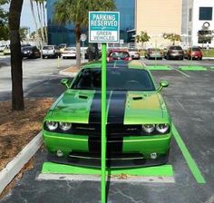 a green and black car is parked in a parking lot next to a parking sign