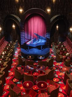 an empty stage with chairs and a piano in the center is lit by red lights