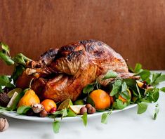 a turkey on a platter with oranges, mushrooms and spinach sprouts