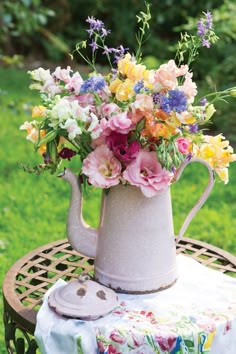 a vase filled with flowers sitting on top of a wooden table in the middle of a field