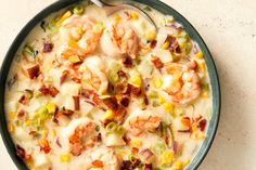 a bowl of soup with shrimp, corn and cheese in it next to a spoon