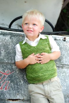 a little boy that is standing in front of a metal box with his hands on his chest