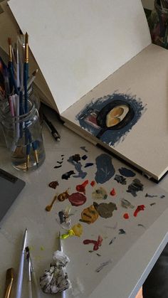 an artist's desk with paint and brushes on it