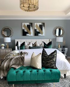 a bed with green velvet pillows and gold accents on the headboard, along with two mirrors above it