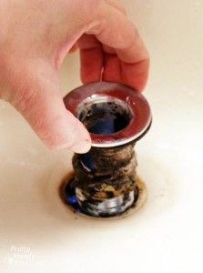 a person's hand reaching into a sink drain