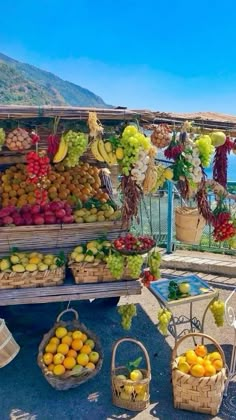 there are many fruits and vegetables on display at the market stall by the water,