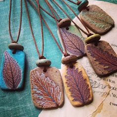 four leaf shaped pendants are sitting on top of a piece of paper and some beads