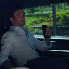 a man sitting in the back seat of a car while holding a cell phone and looking up