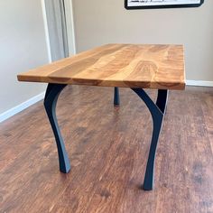 a wooden table sitting on top of a hard wood floor next to a white wall