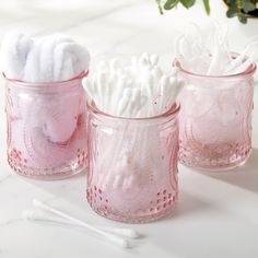 three glass jars with toothbrushes in them