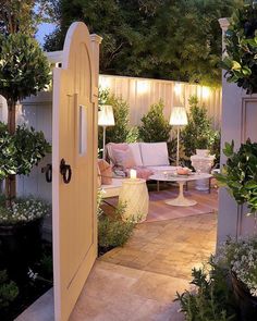 an outdoor living area with couches, tables and trees in the background at night