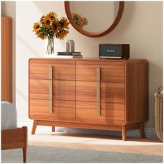 a wooden dresser with flowers and a clock on it's sideboard in front of a round mirror