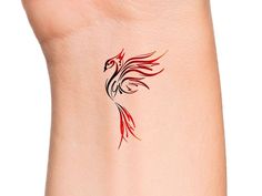 a red and black bird tattoo on the side of a woman's right arm