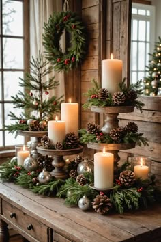 christmas candles are arranged on a table with pine cones and evergreen branches in the center