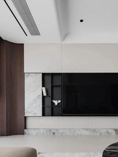 a modern living room with white marble walls and flooring, along with a large tv mounted on the wall