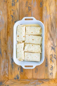 tortillas in a white casserole dish on a wooden table