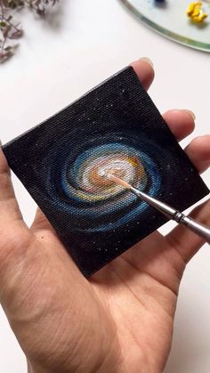 a person holding a paintbrush in their left hand and painting the inside of a canvas