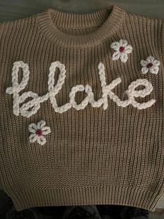 a sweater with the word bake written on it and flowers in front of it