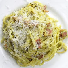 a white plate topped with pasta covered in parmesan cheese