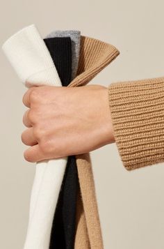 a woman's hand is wrapped in two different colored sweaters