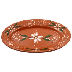 an orange platter with white flowers and green leaves on the rim, sitting on a white background