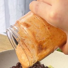 a person pouring dressing into a bowl of grapes