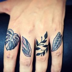 a woman's hand with two tattoos on her fingers and one has a leaf