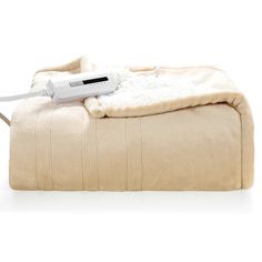 an electric blanket is sitting on top of a white ottoman with a heater plugged into it