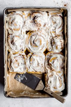 a pan filled with cinnamon rolls covered in icing