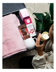 a woman sitting on a couch holding a cup and some items in front of her