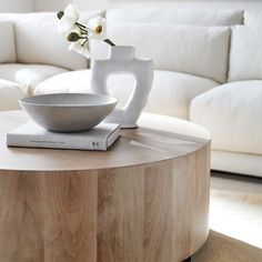 a table with a bowl and book on it in front of a white sectional couch