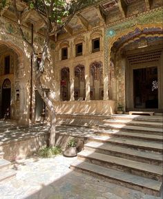 an ornate building with steps leading up to it and a tree in the foreground