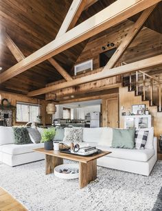 a living room filled with lots of furniture and wooden beams on the ceiling over a white rug