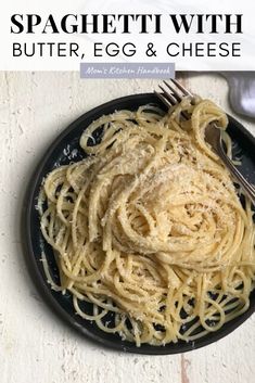 spaghetti with butter, egg and cheese on a black plate next to a silver fork