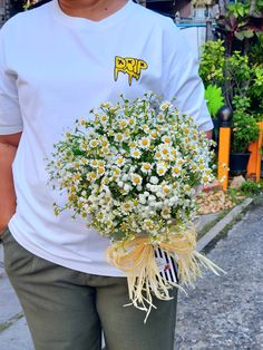 a man holding a bouquet of daisies on the street