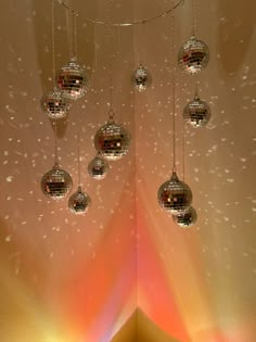 several disco balls hanging from a ceiling in front of a rainbow colored wall with lights