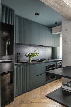 a kitchen with green cabinets and black counter tops in the middle of an open floor plan