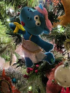 a blue stuffed animal ornament hanging from a christmas tree with ornaments around it