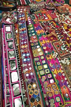 a woman standing next to a pile of colorful cloths on top of a table